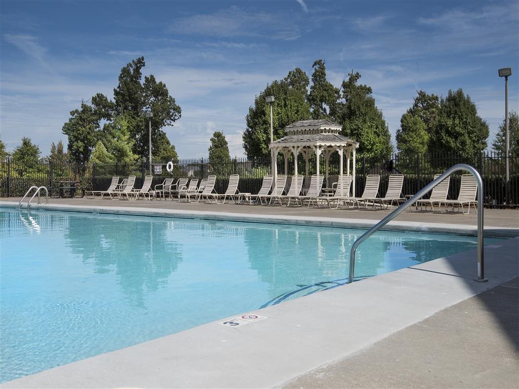 A pool with a gazebo and sun loungers in the background.
