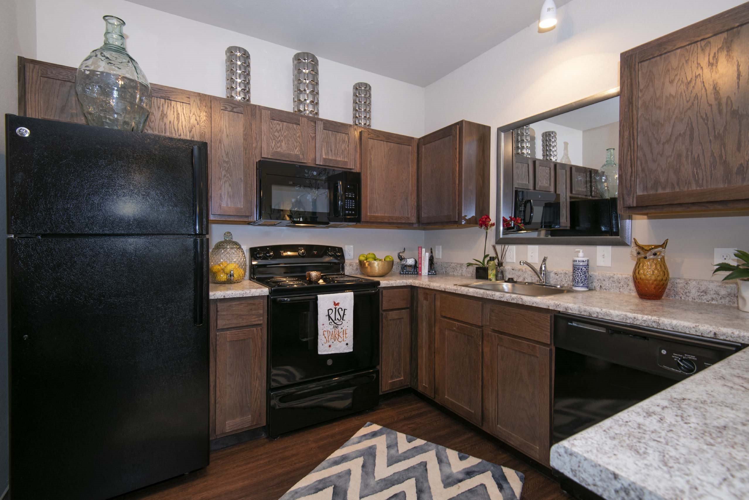 A kitchen with black appliances and wooden cabinets.