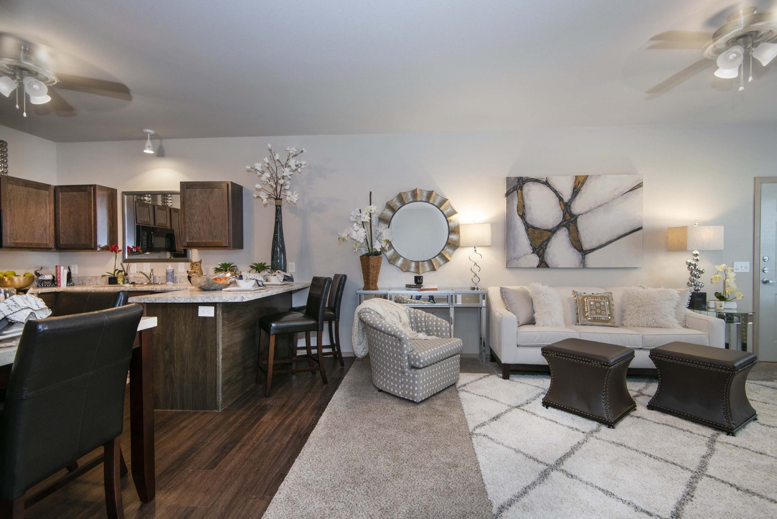 A well-lit, modern living room with a kitchen area in the background.