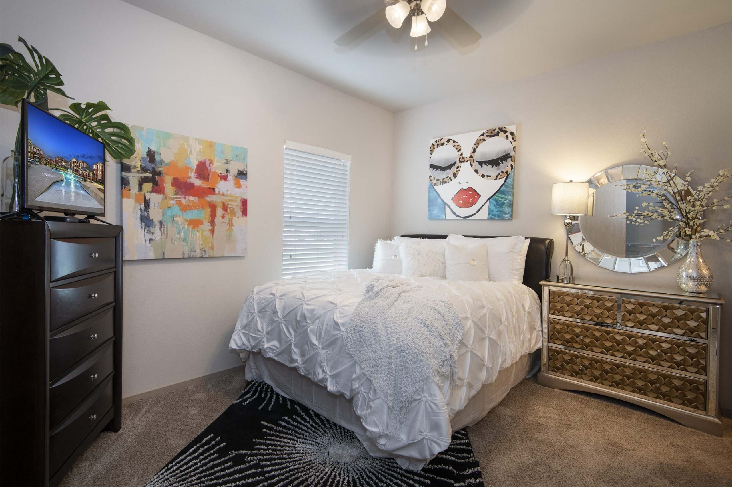 A bedroom with a bed, dresser, and a painting on the wall.