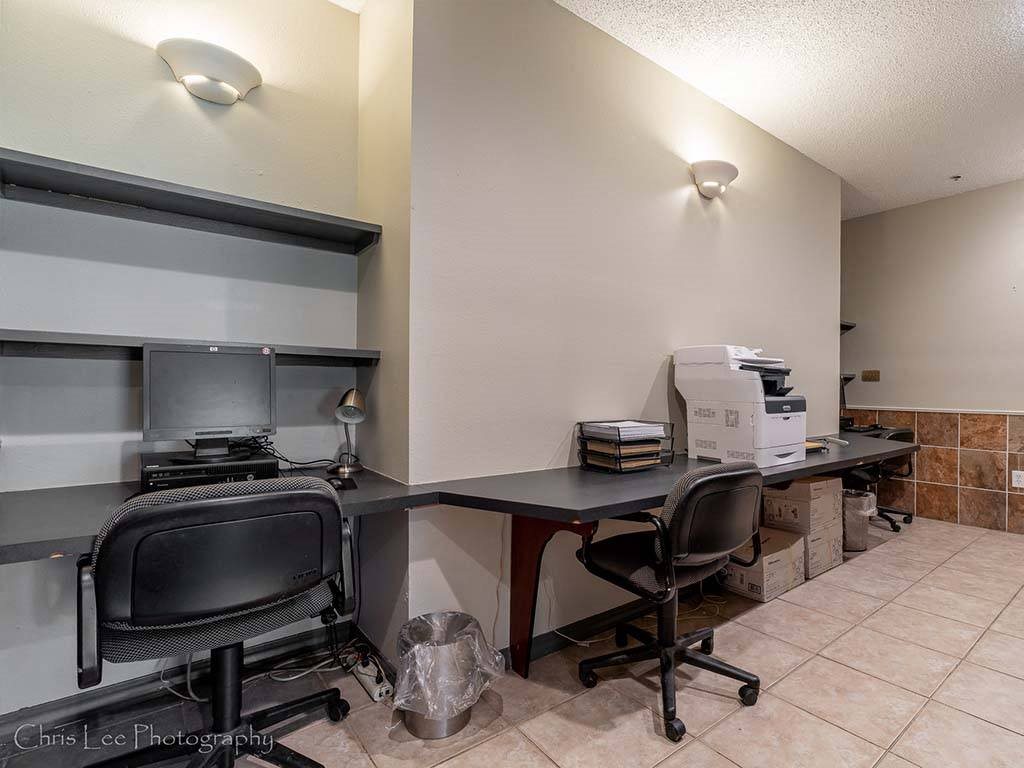 A room with a desk, chairs, and boxes on the floor.