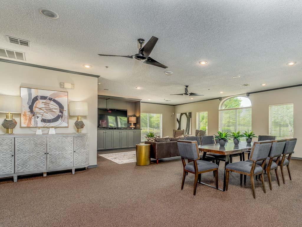 A spacious room with a dining table set up with chairs and a ceiling fan.