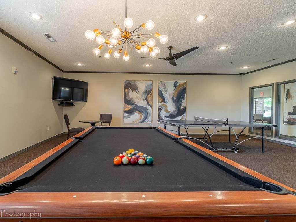 A pool table with a television and a painting in the background.