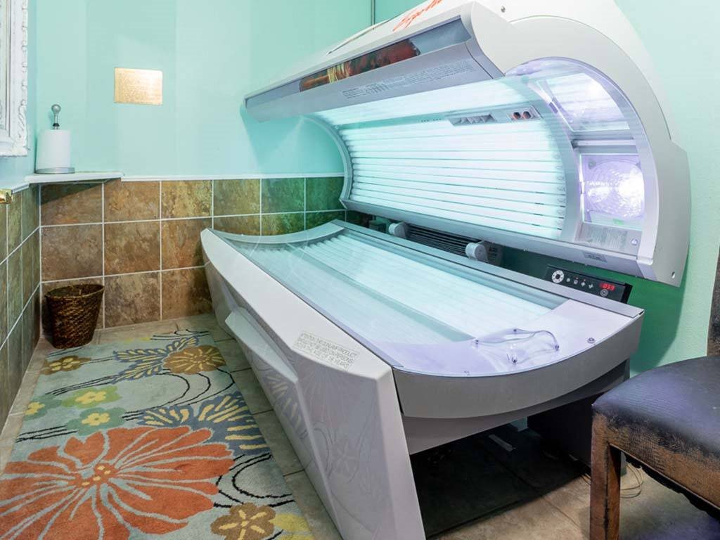 A tanning bed in a room with a colorful floor mat.