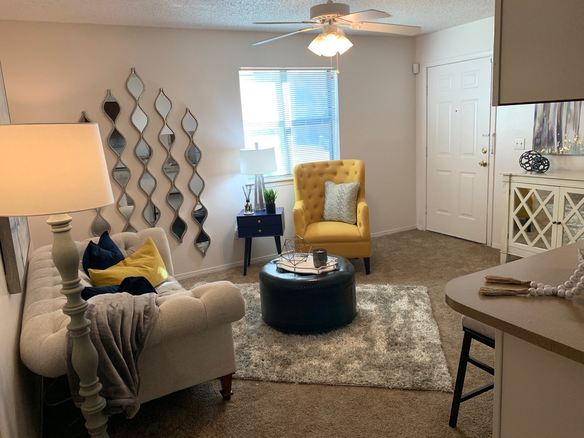 A living room with a yellow chair and a white couch.