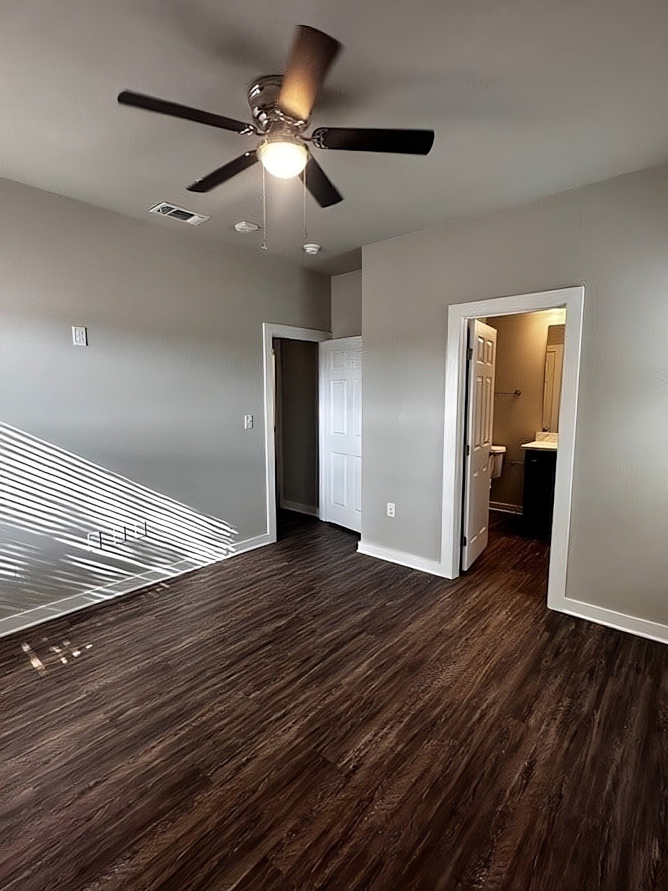 A room with a ceiling fan and a wooden floor.