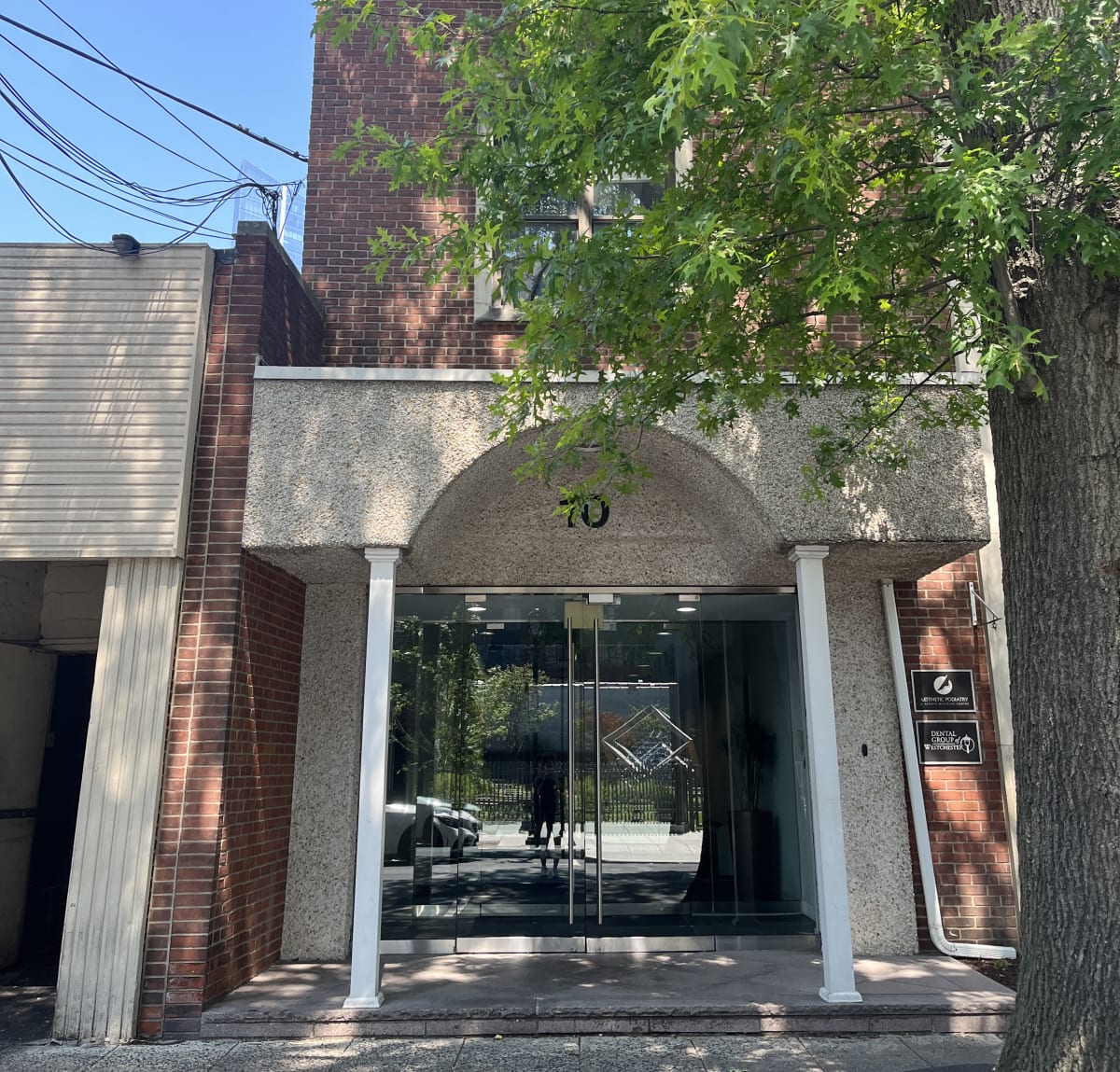 A building with a large arched entrance and a tree in front.,A building with a large arched entrance and a tree in front.