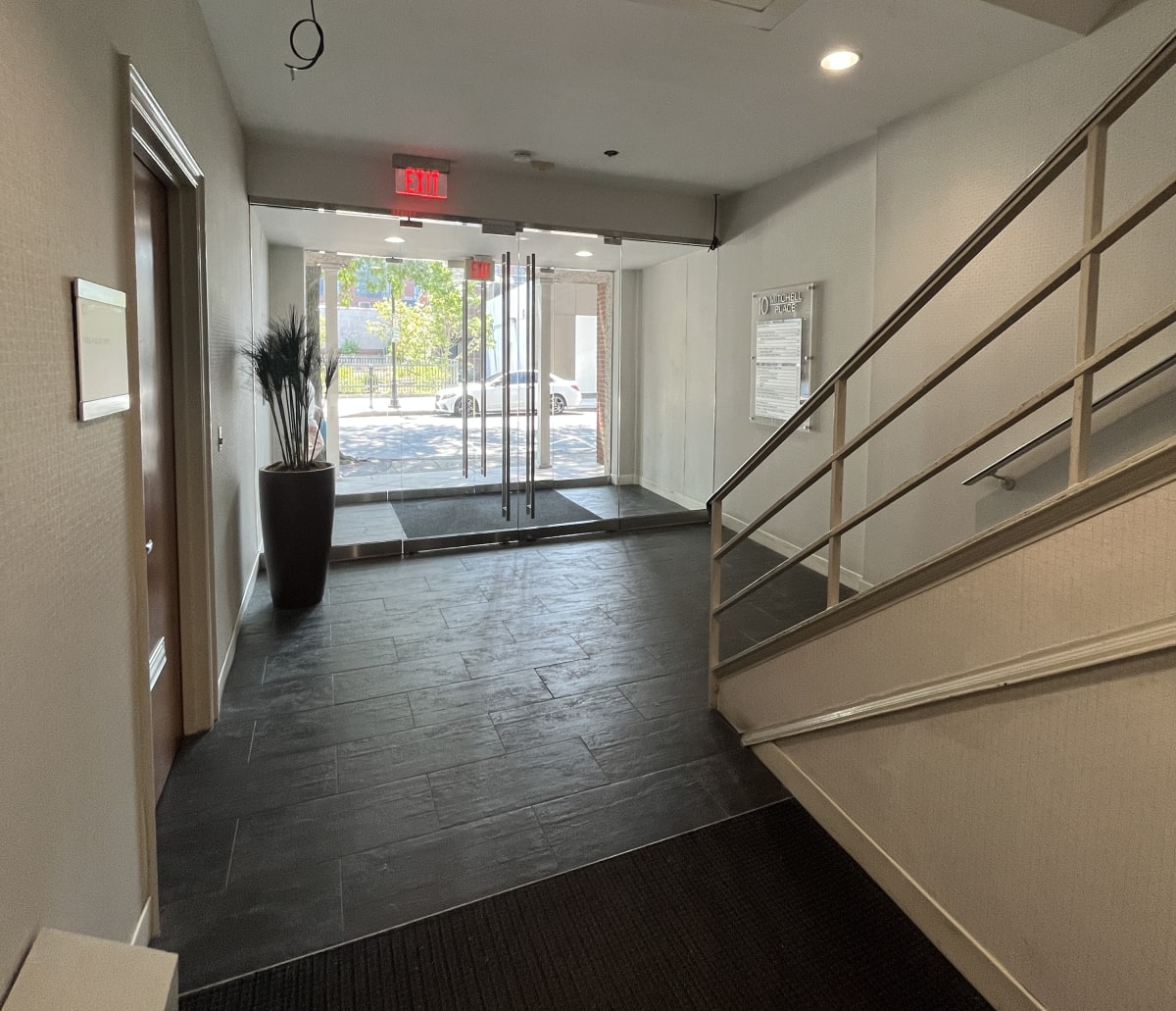 A hallway with a red exit sign above the door.