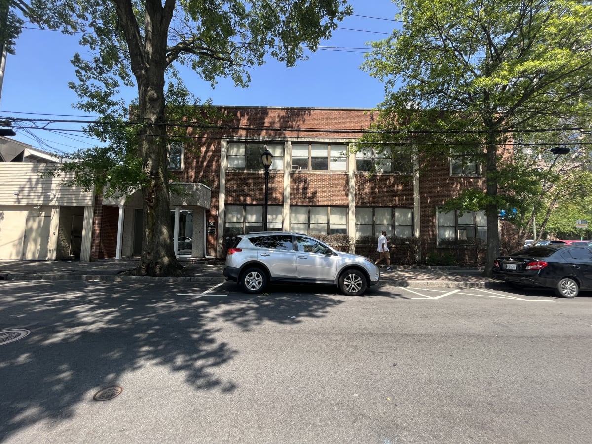 A silver car is parked in a parking lot in front of a building.