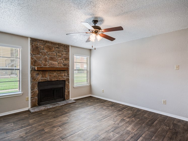 Living Room with Fireplace and Ceiling Fan at Bookstone and Terrace Apartments in Irving, Texas