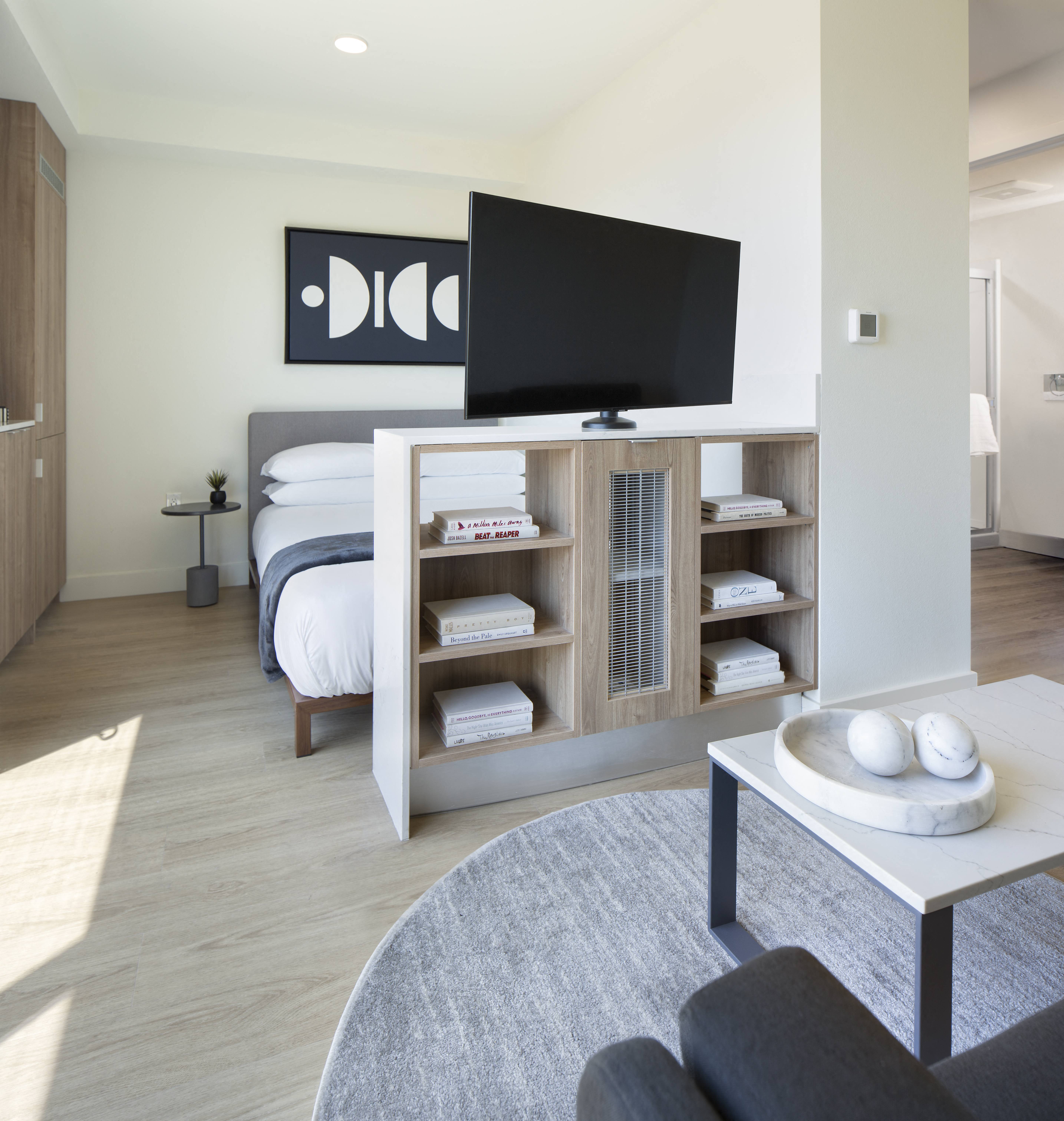 a bedroom with a tv on top of a bookshelf