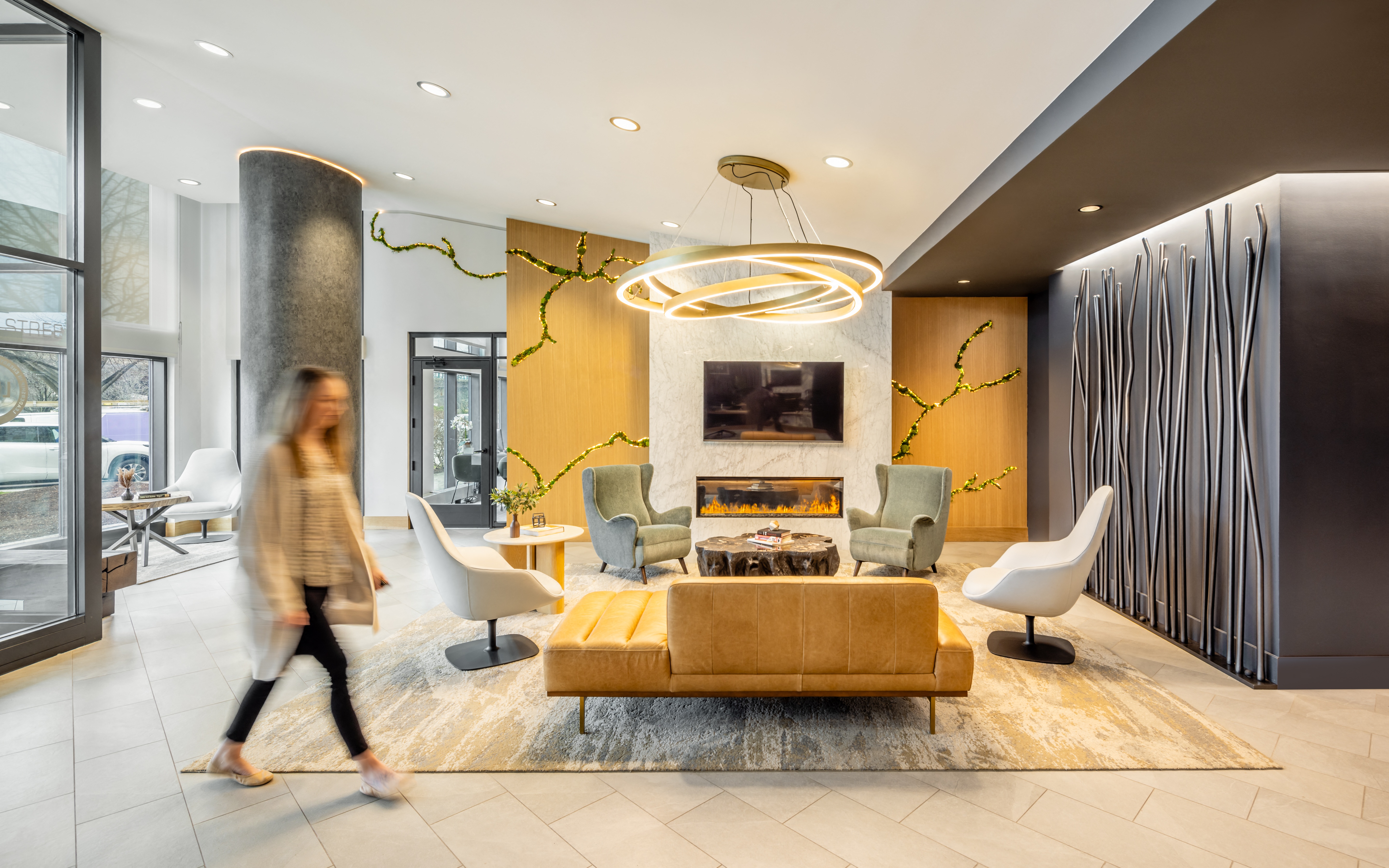 A woman walks through a modern living room with a yellow couch.