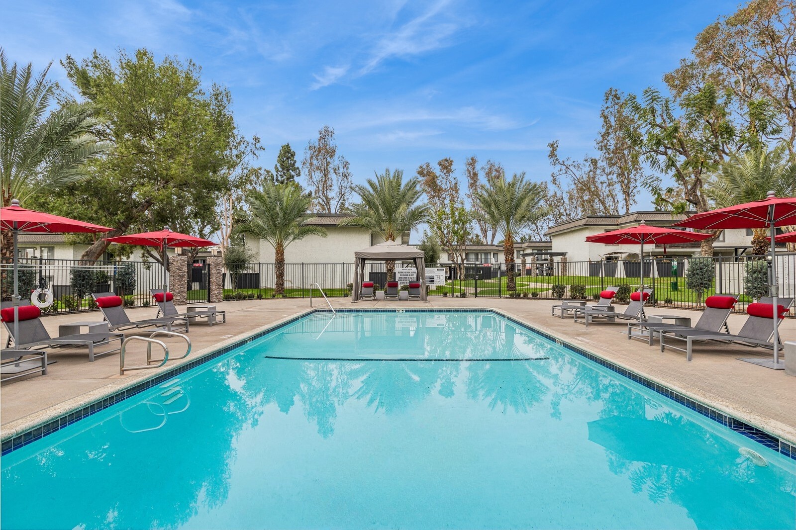A large swimming pool surrounded by lounge chairs and umbrellas.