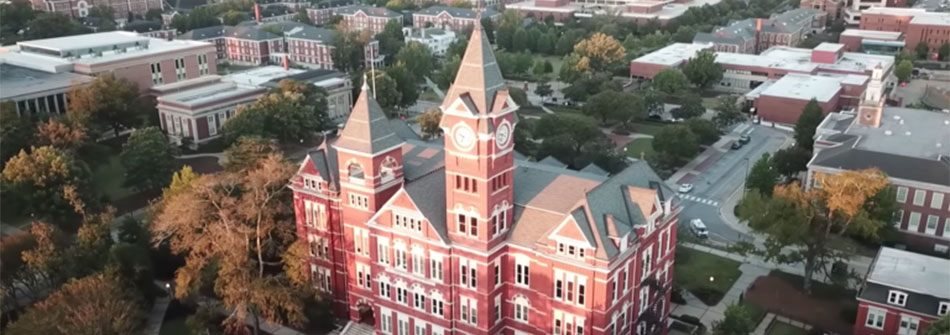 A large red building with a tower is surrounded by trees.