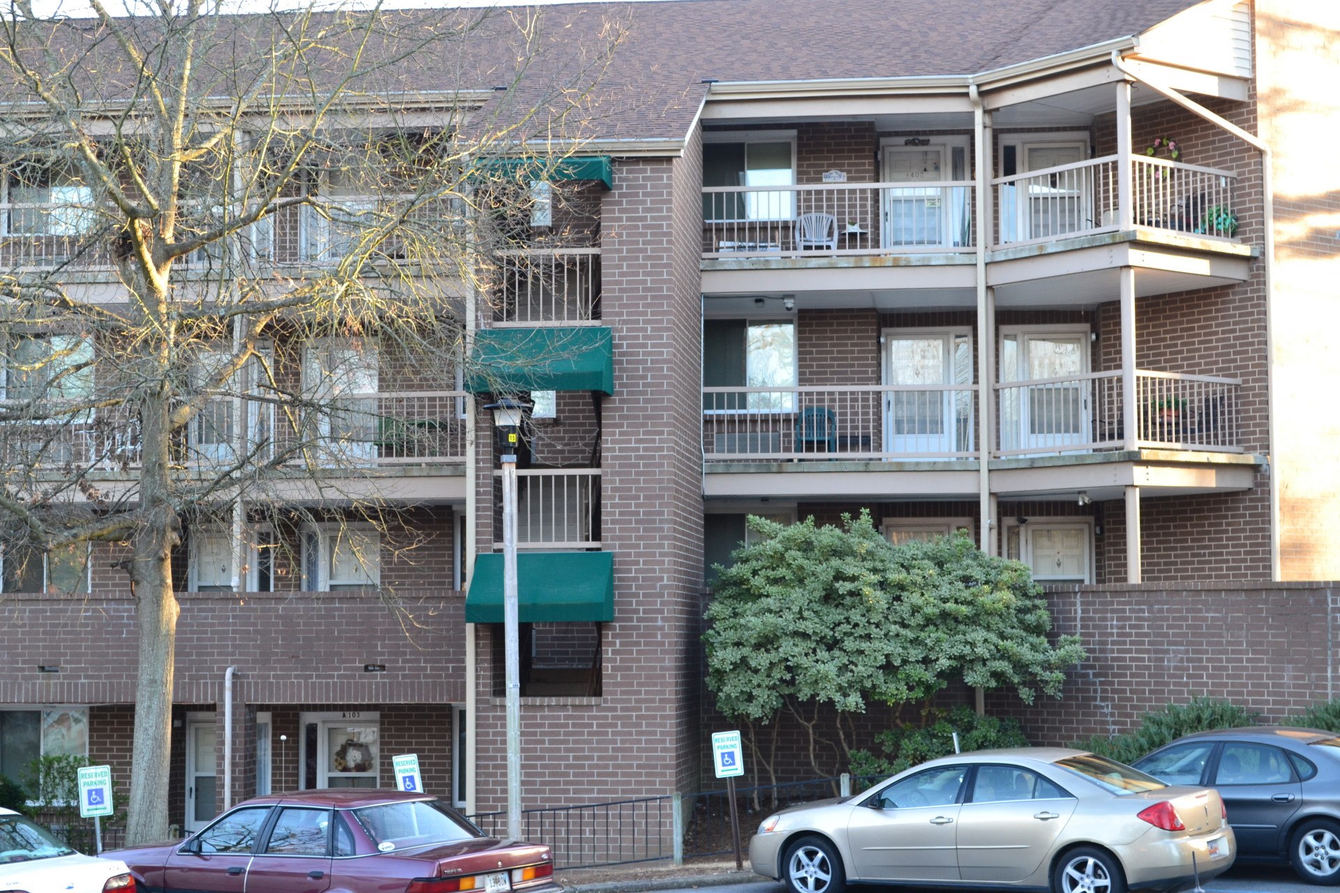 a brick apartment building with cars parked in front
