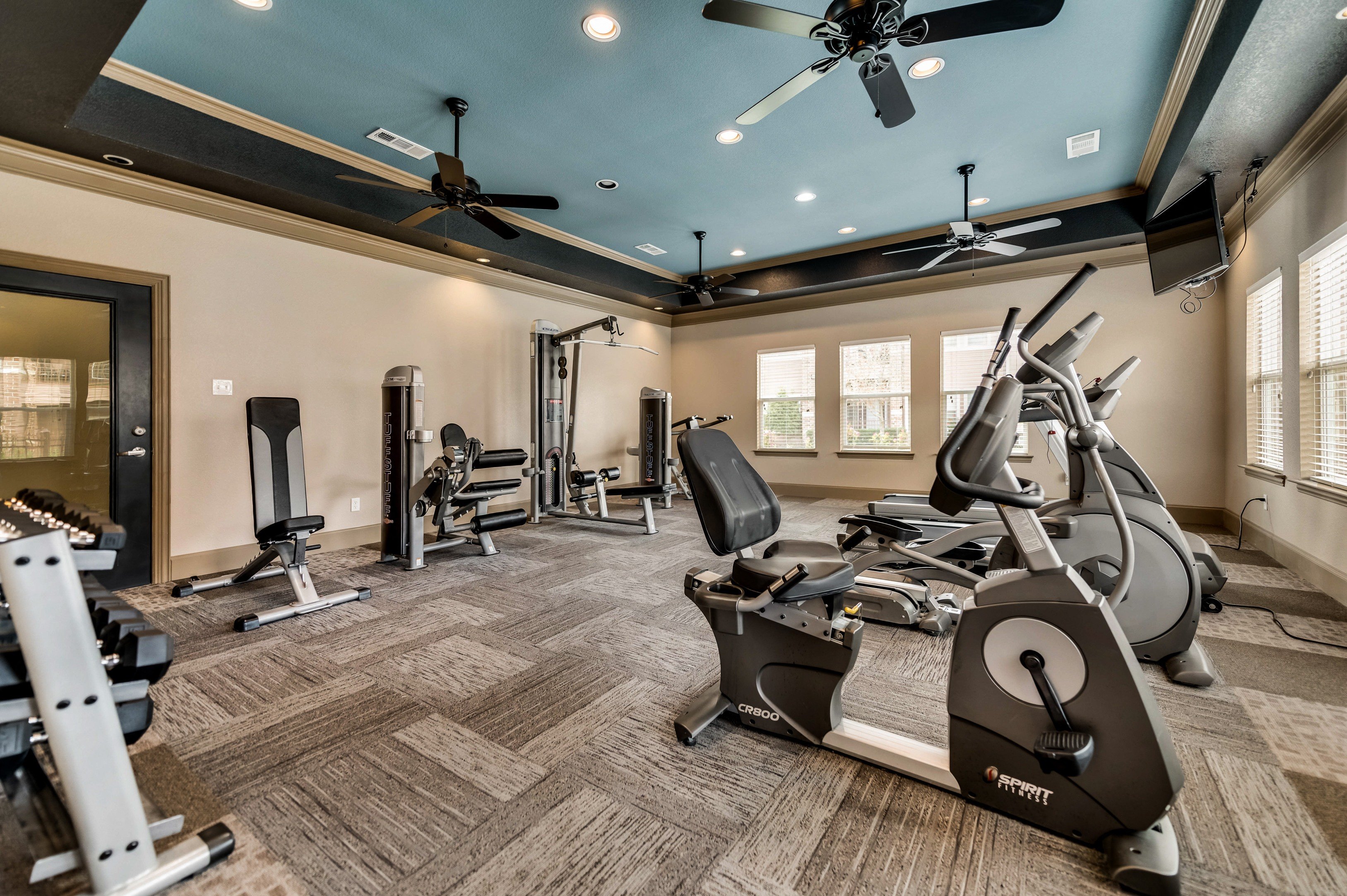 Fitness center with cardio equipment and free weights at Timber Creek Apartments in Sulphur Springs, TX
