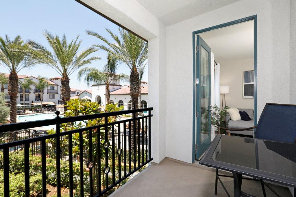 a balcony with a view of a pool and palm trees