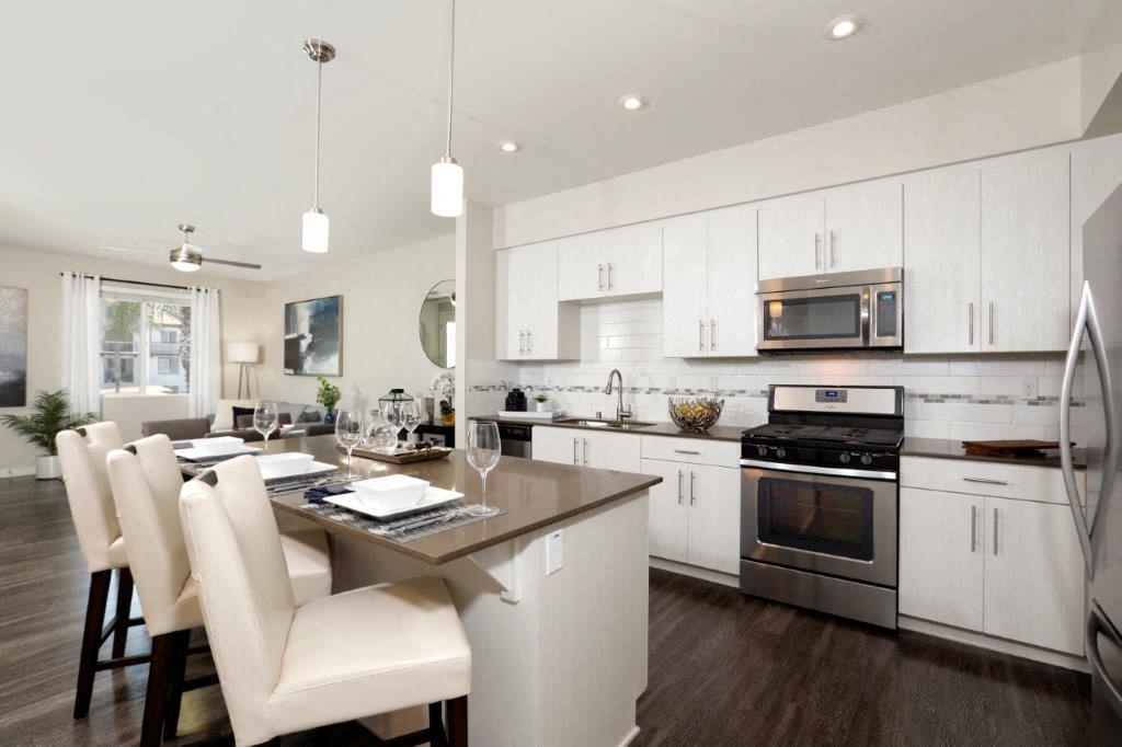 an open kitchen and dining area with white cabinets and stainless steel appliances