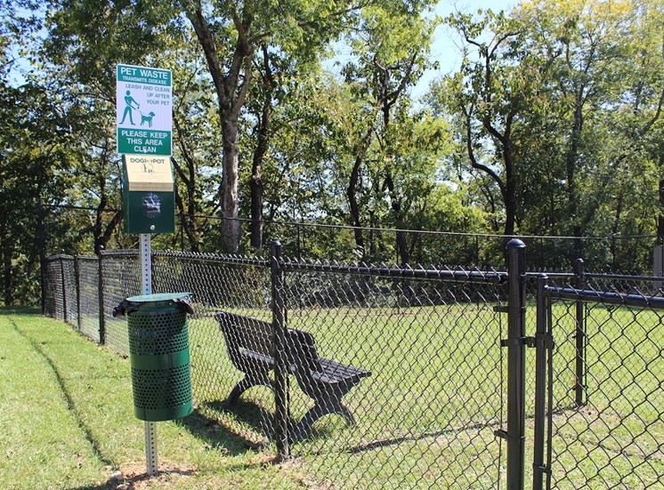Fenced dog park with bench and waste disposal station