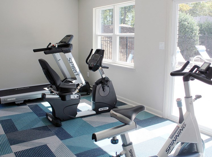 Cardio exercise equipment in front of windows and glass door to pool