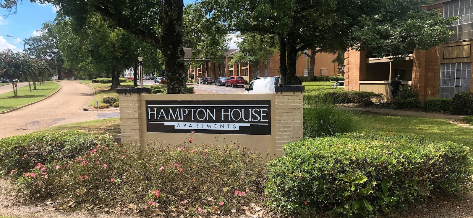 Sign with Property Logo surrounded by beautiful green landscaping at Hampton House Apartments