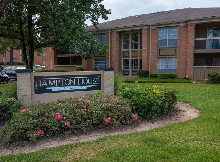 Monument sign surrounded by flowers in front of Hampton House Apartments