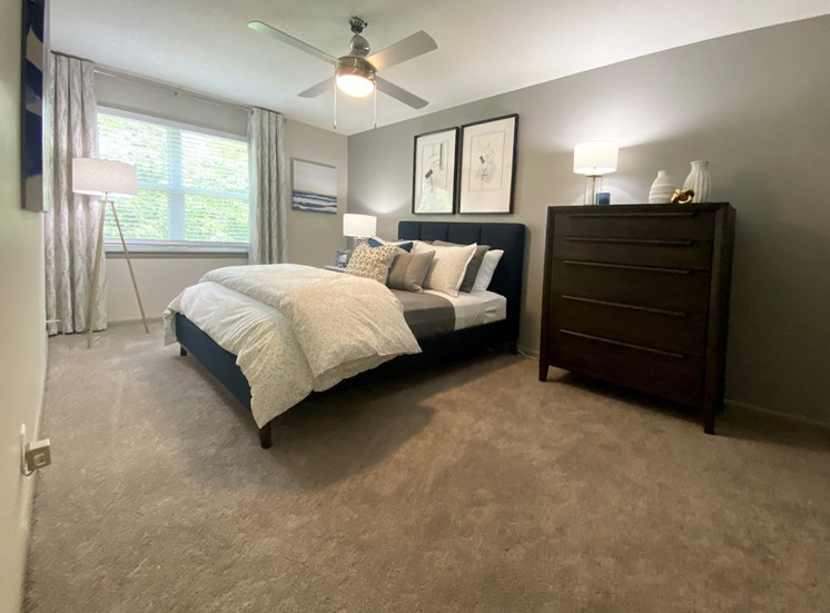 bedroom with large window, fan, carpet and model furnishings