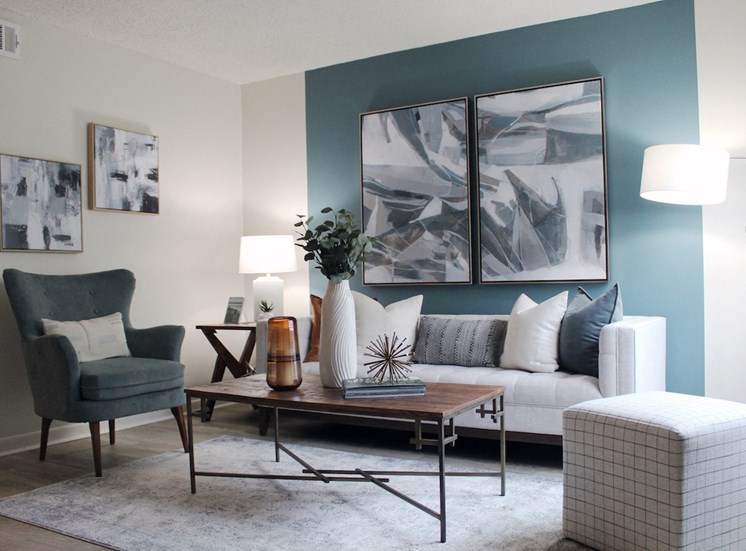living room with hardwood-style flooring and teal accent wall and model furniture