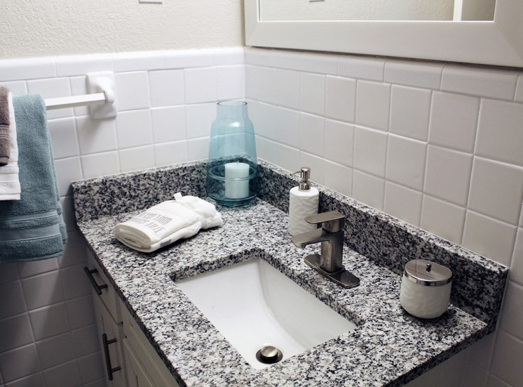 granite vanity in bathroom with under-mount sink, modern fixtures, and tile walls