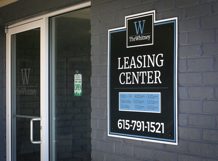 leasing center entrance with sign showing hours of operation