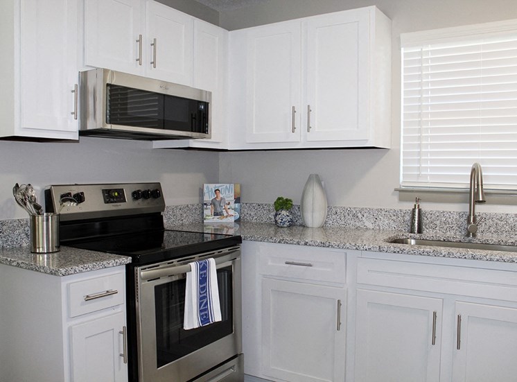 Model kitchen with granite countertops, stainless steel stove, and built-in microwave