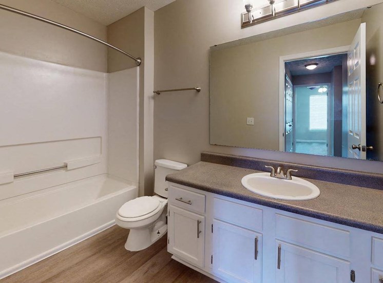 large sink vanity, mirror, toilet, and tub and shower