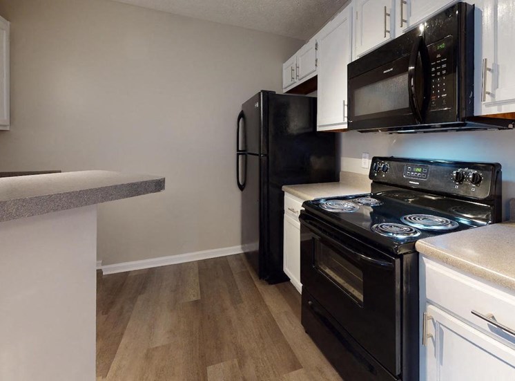 kitchen with black appliances, mounted microwave, and wood-style flooring