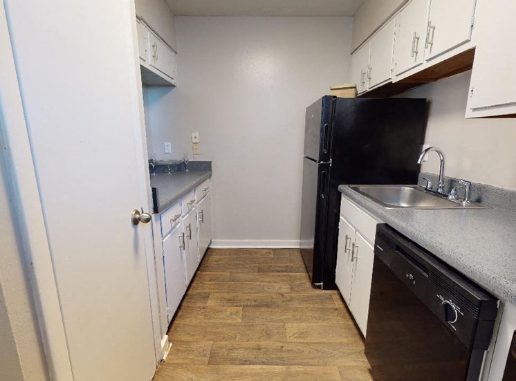 Kitchen with white cabinets, grey countertops, and black appliances at Reserve at Midtown Apartments in Tallahassee, Florida 32303