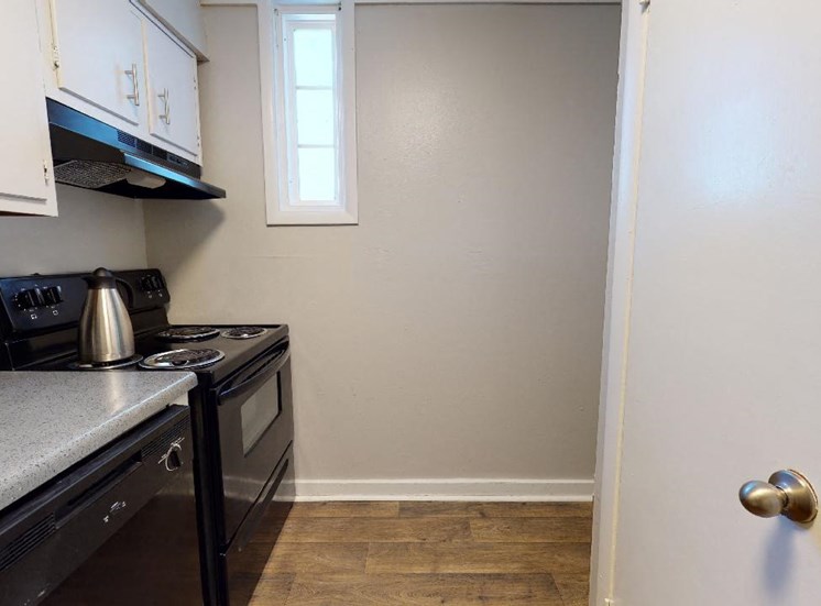 Kitchen with black appliances, wood-style flooring, and white cabinetry at Reserve at Midtown Apartments in Tallahassee, Florida 32303