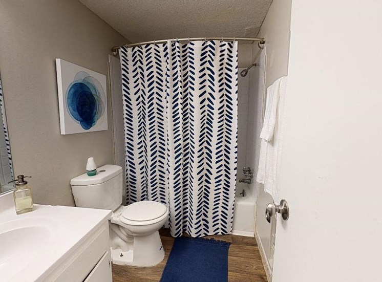 Bathroom with wood-style floors, tub & shower, toilet, and vanity at Reserve at Midtown Apartments in Tallahassee, FL