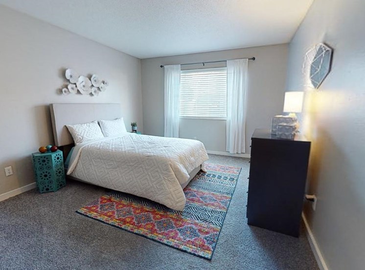 Bedroom with model furnishings, carpet, and large window at Reserve at Midtown Apartments in Tallahassee, Florida