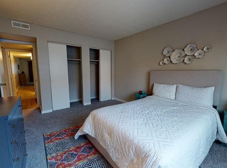 Large bedroom with double closets, carpet, and model furnishings at Reserve at Midtown Apartments in Tallahassee, Florida 32303