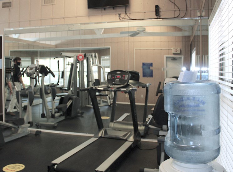 fitness center with cardio equipment in front of large mirror