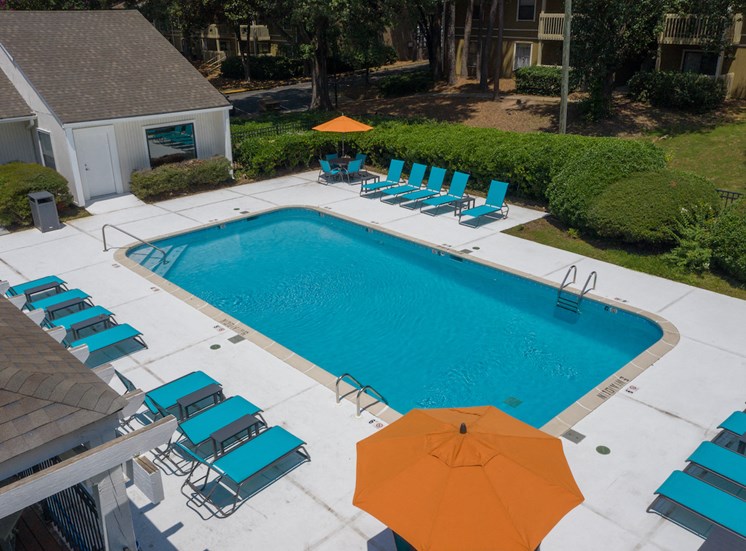 rows of lounge chairs, picnic tables with umbrellas, and pool at Zelda Pointe Apartments