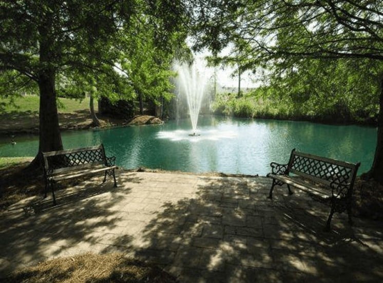 Pond with benches and fountain surrounded by trees at Stillwater at Grandview Cove, Simpsonville, SC, 29680