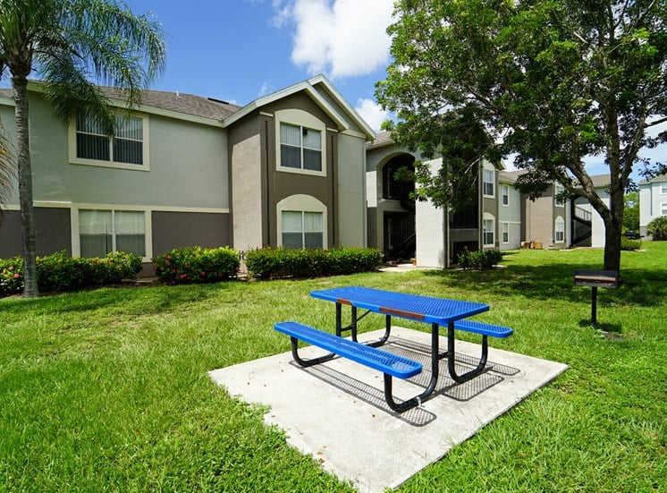Outdoor picnic area surrounded by native landscaping and apartment building exterior in the background