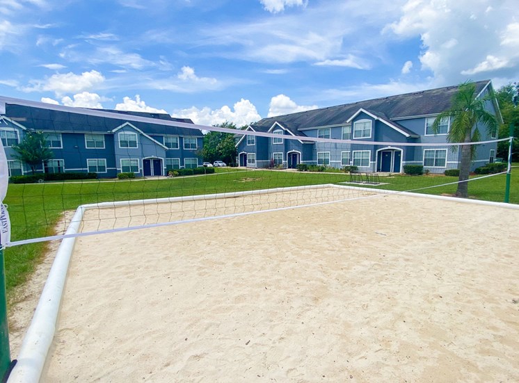Sand volleyball court with trees and building exteriors  in the background