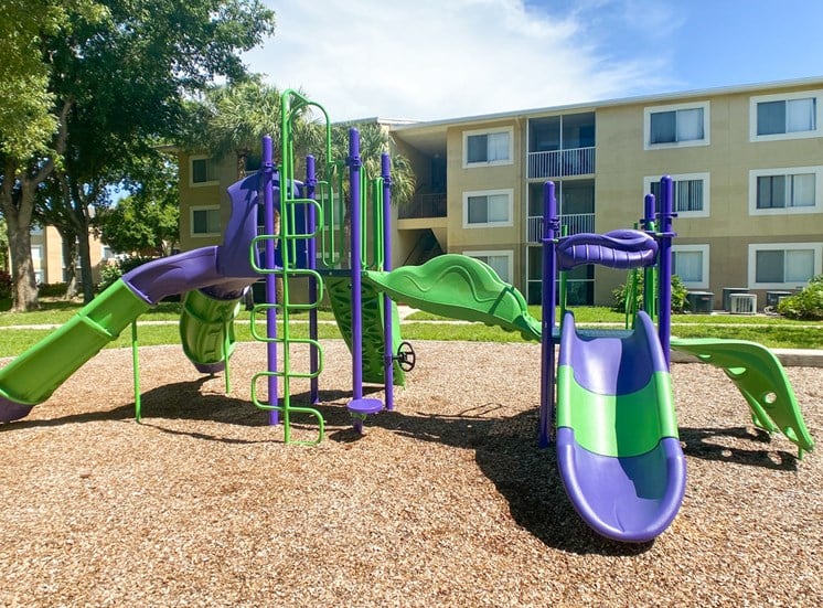 Purple and Green Playground on Mulch with Building Exterior in the Background