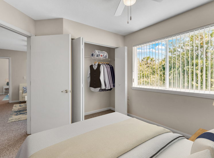 Virtually staged bedroom with large reach-in closet, multi speed ceiling fan, carpet flooring, and window for natural lighting
