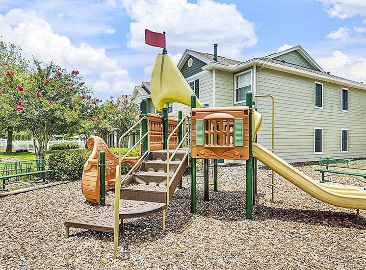 Playground in bed of mulch and yellow slide.