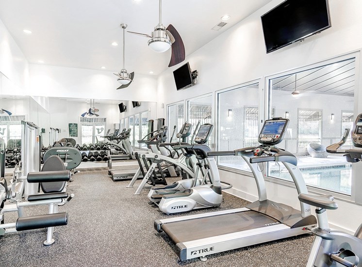 Fitness center equipped with strength training equipment, cardio equipment, and yoga equipment overlooking indoor pool