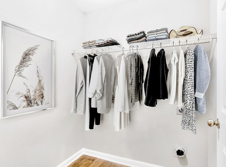 Staged spacious closet filled with clothes and art on the wall .
