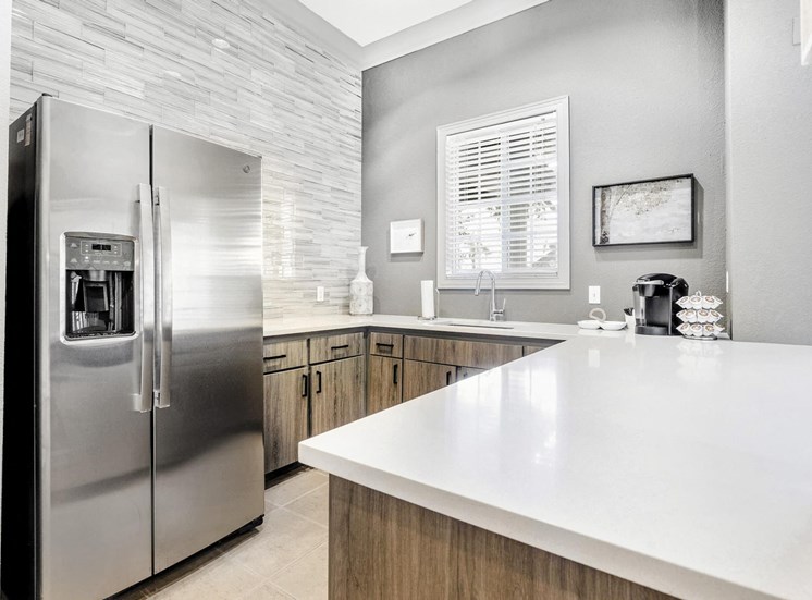 Clubhouse kitchen with white countertops, a sink, and a stainless steel french door refrigerator.