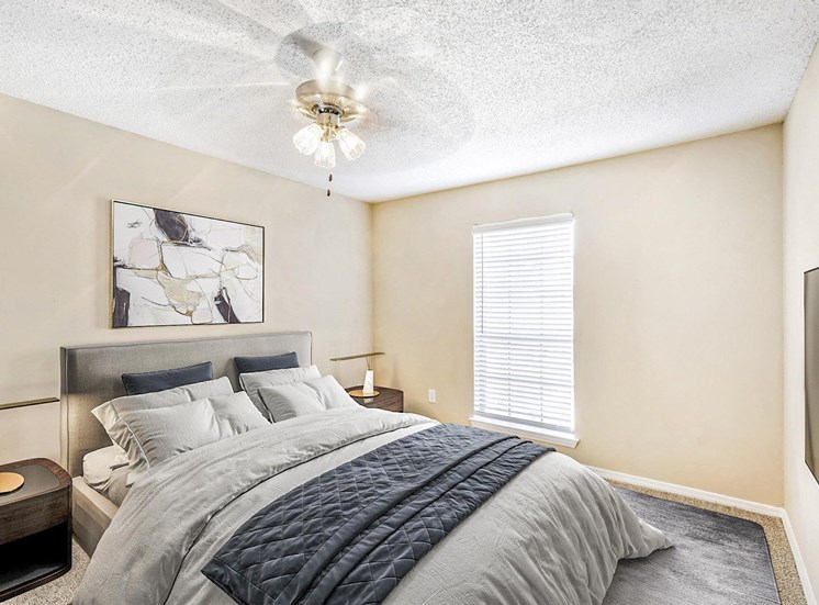Bedroom with queen size bed, night stand with lamp and a ceiling fan